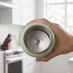 A hand holding the bottom of a light green vacuum-insulated tumbler, showing the bottle is made of 316 stainless steel