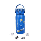 A blue insulated water bottle with a matching blue carry handle lid, decorated with cartoon graphics including a skateboard, stars, and a crown. Four small accessory charms are arranged below the bottle on a plain white background.